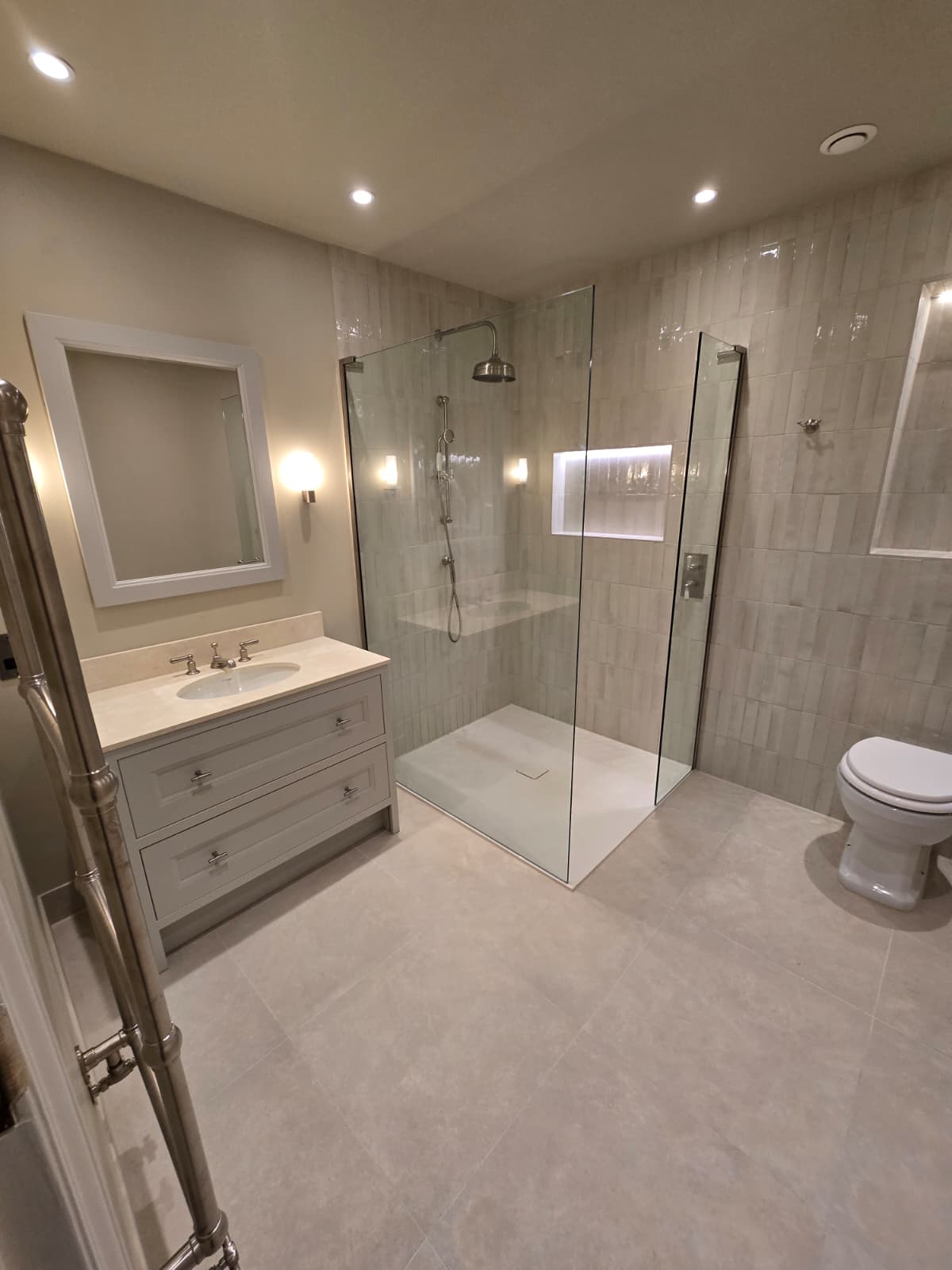 Renovated bathroom with grey shaker vanity, limestone floor and walk-in glass shower